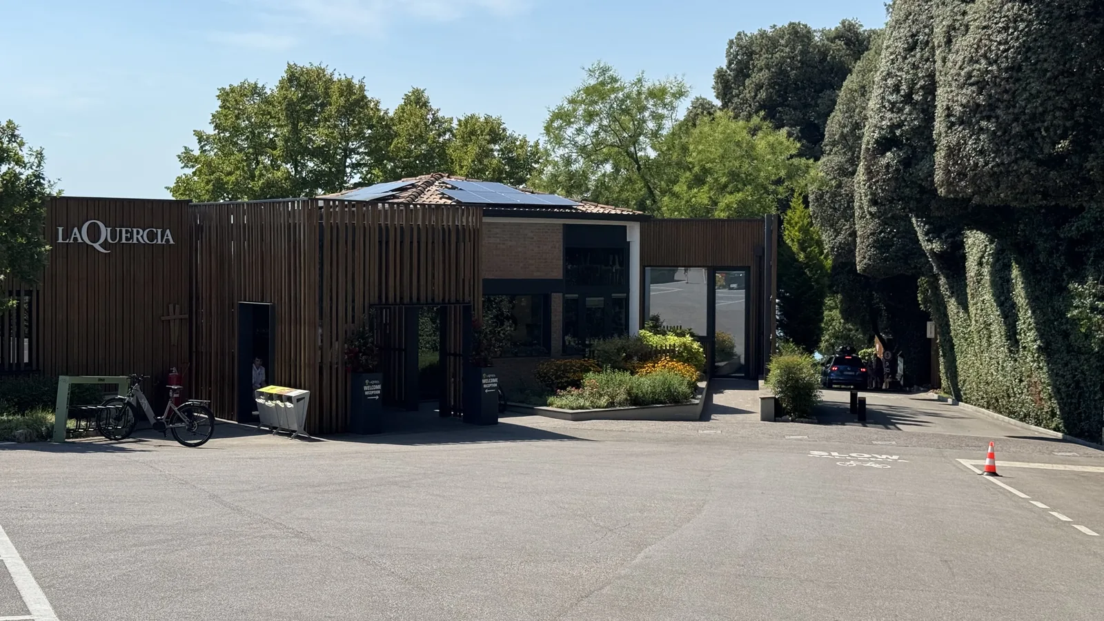 Empfangsgebäude des Camping La Quercia mit Holzlamellen-Fassade und großem Schriftzug LA QUERCIA