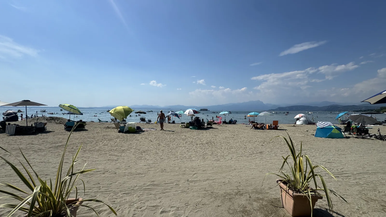 Blick längs über den geharkten Sandstrand des Camping La Quercia mit mehreren Metern freiem Sand vor den Sonnenschirmreihen