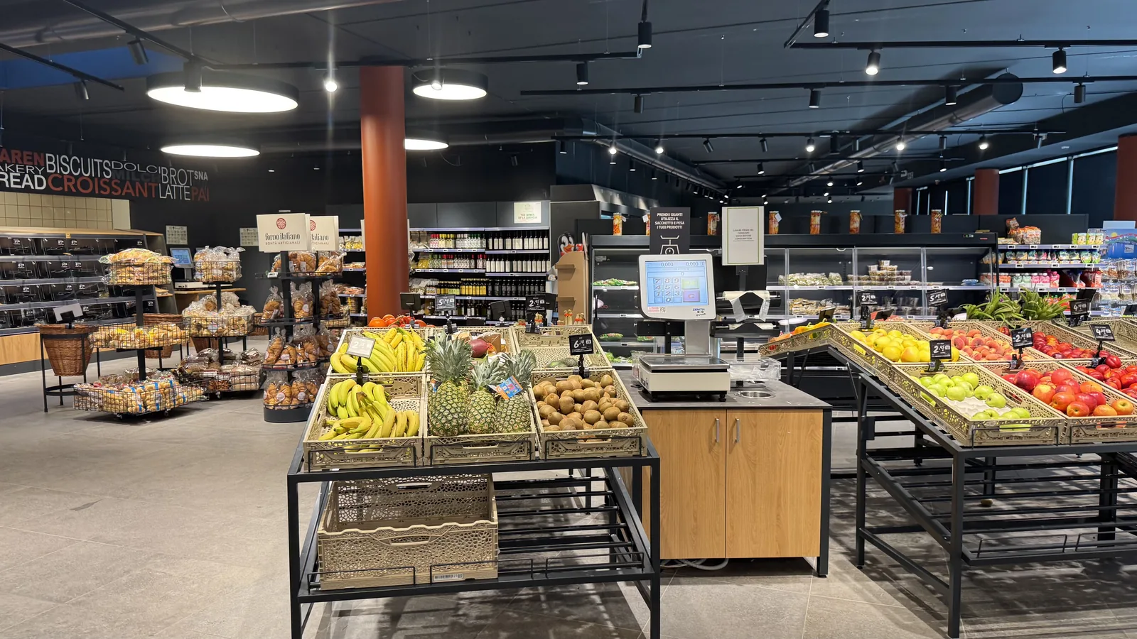 Innenansicht des Supermarkts am Camping La Quercia mit Obstinseln, Backwaren und Kühltheken