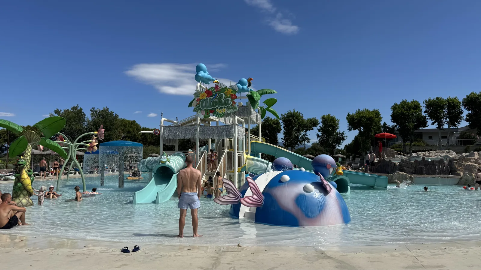 Flaches Kinderbecken mit Wal- und Fischfiguren, Wasserpilz und Kletterturm auf Camping Piani di Clodia
