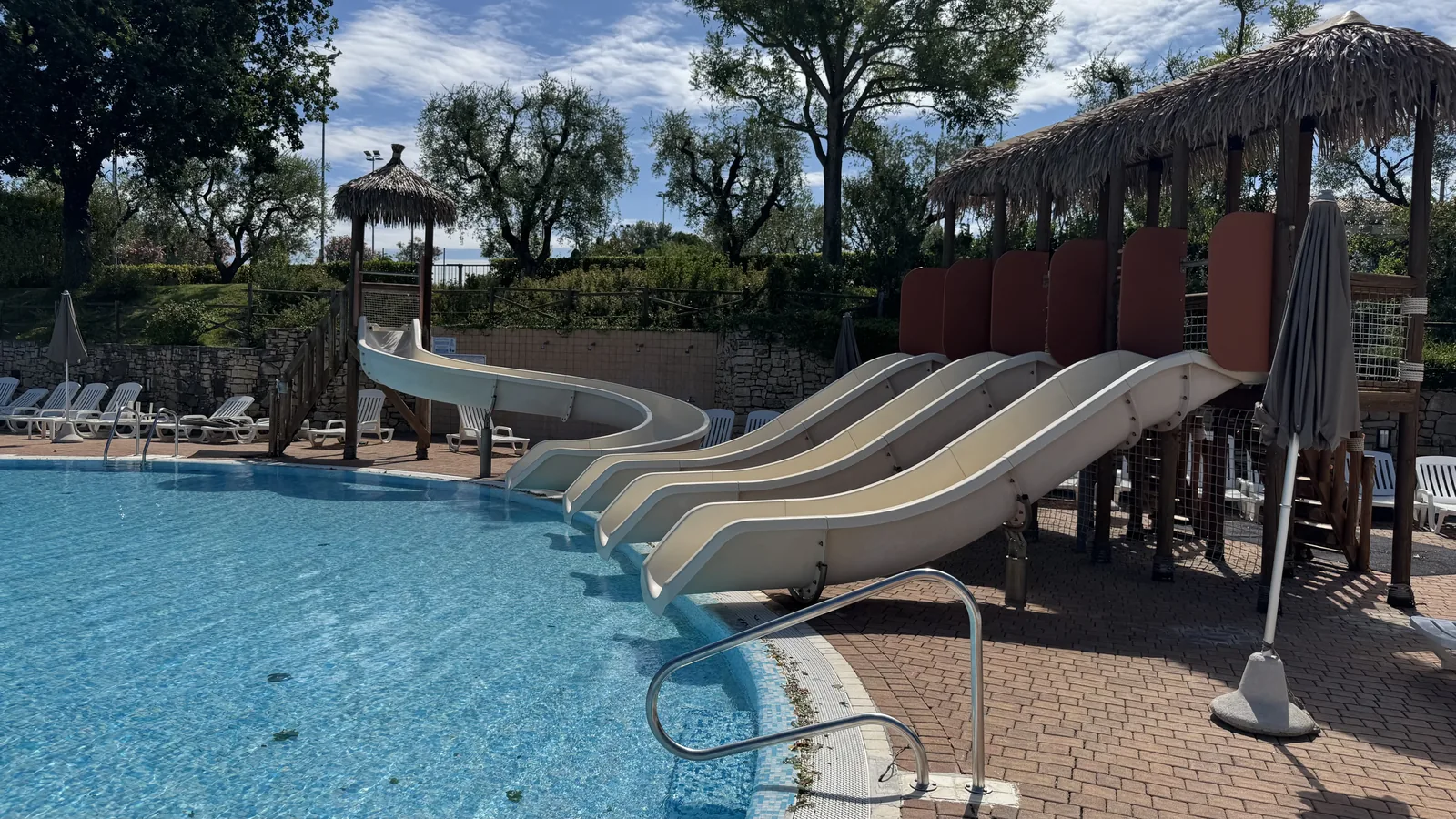 Vierbahnige Breitrutsche und Kurvenrutsche im Wasserpark von Camping Piani di Clodia mit Strohdach-Pavillons