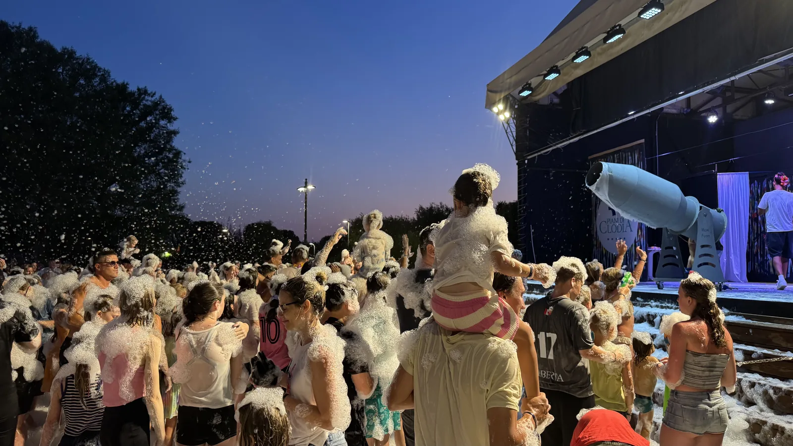 Schaumkanone auf der Freilichtbühne von Camping Piani di Clodia in der Dämmerung, Publikum steht im Schaum