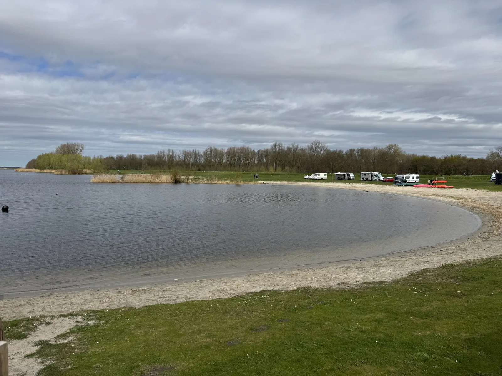 Sandige Badebucht am Eemmeer mit Grasufer, am gegenüberliegenden Ufer stehen Wohnmobile