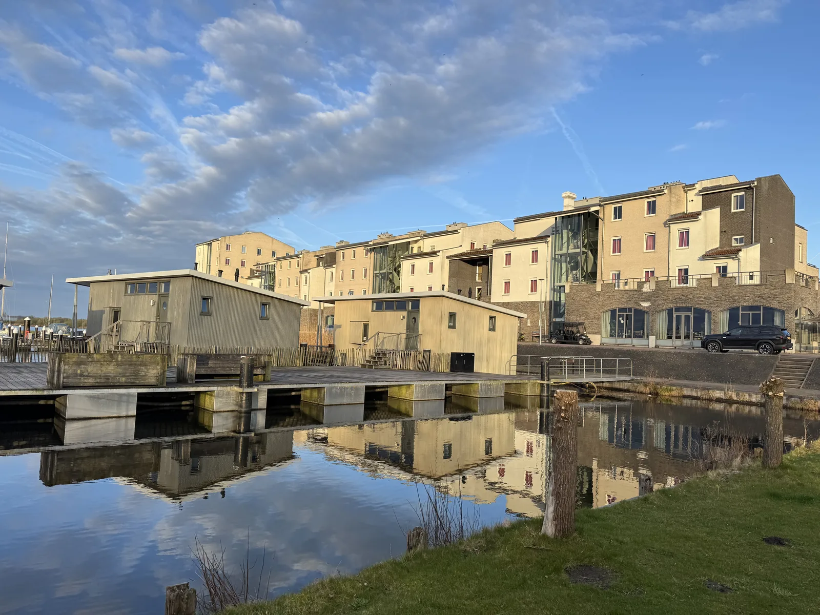 Sandfarbene Reihenhauszeile am Hafenbecken, komplett im ruhigen Wasser gespiegelt