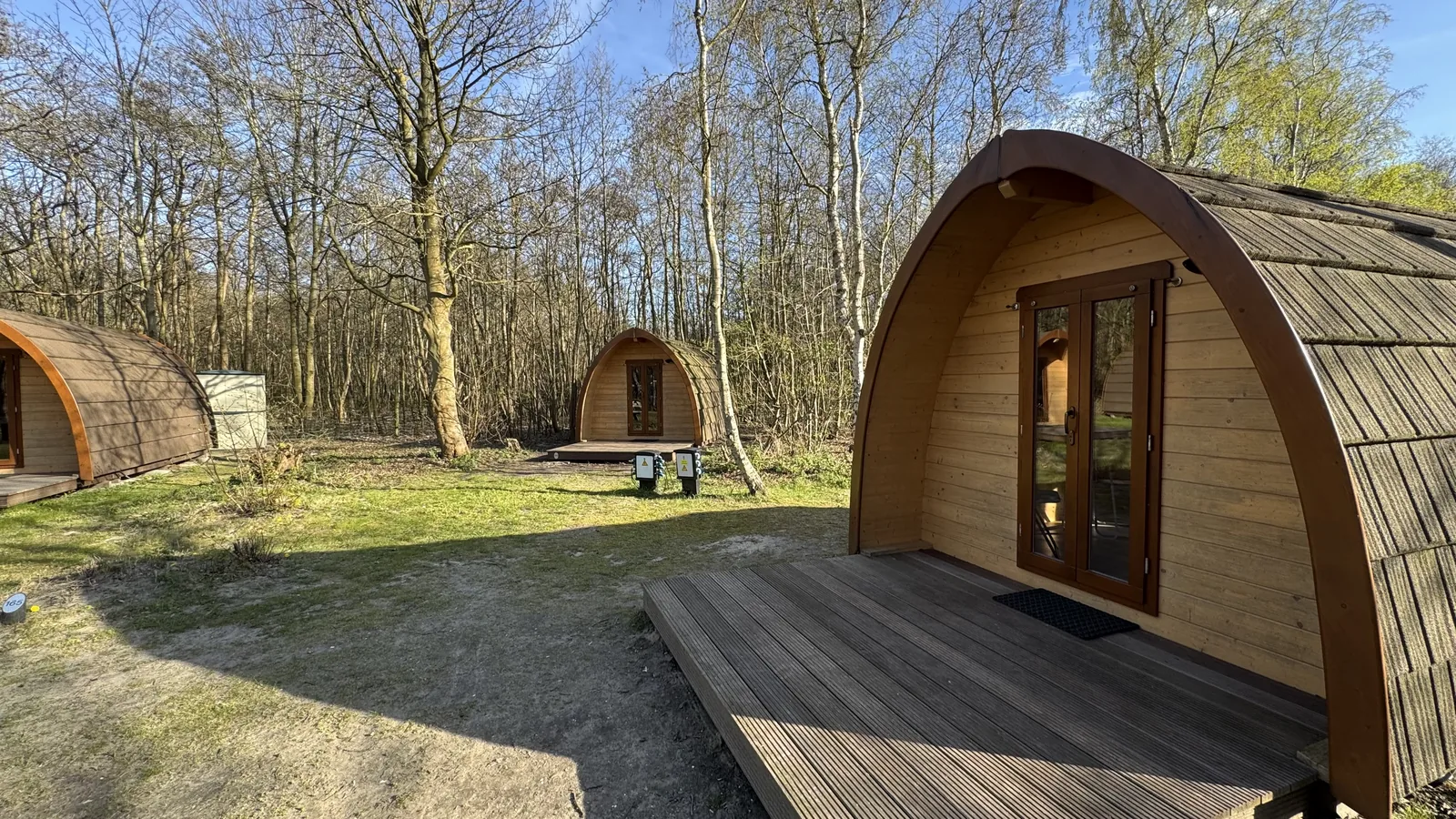 Campingfass mit Glastür und vorgelagerter Holzterrasse im warmen Abendlicht