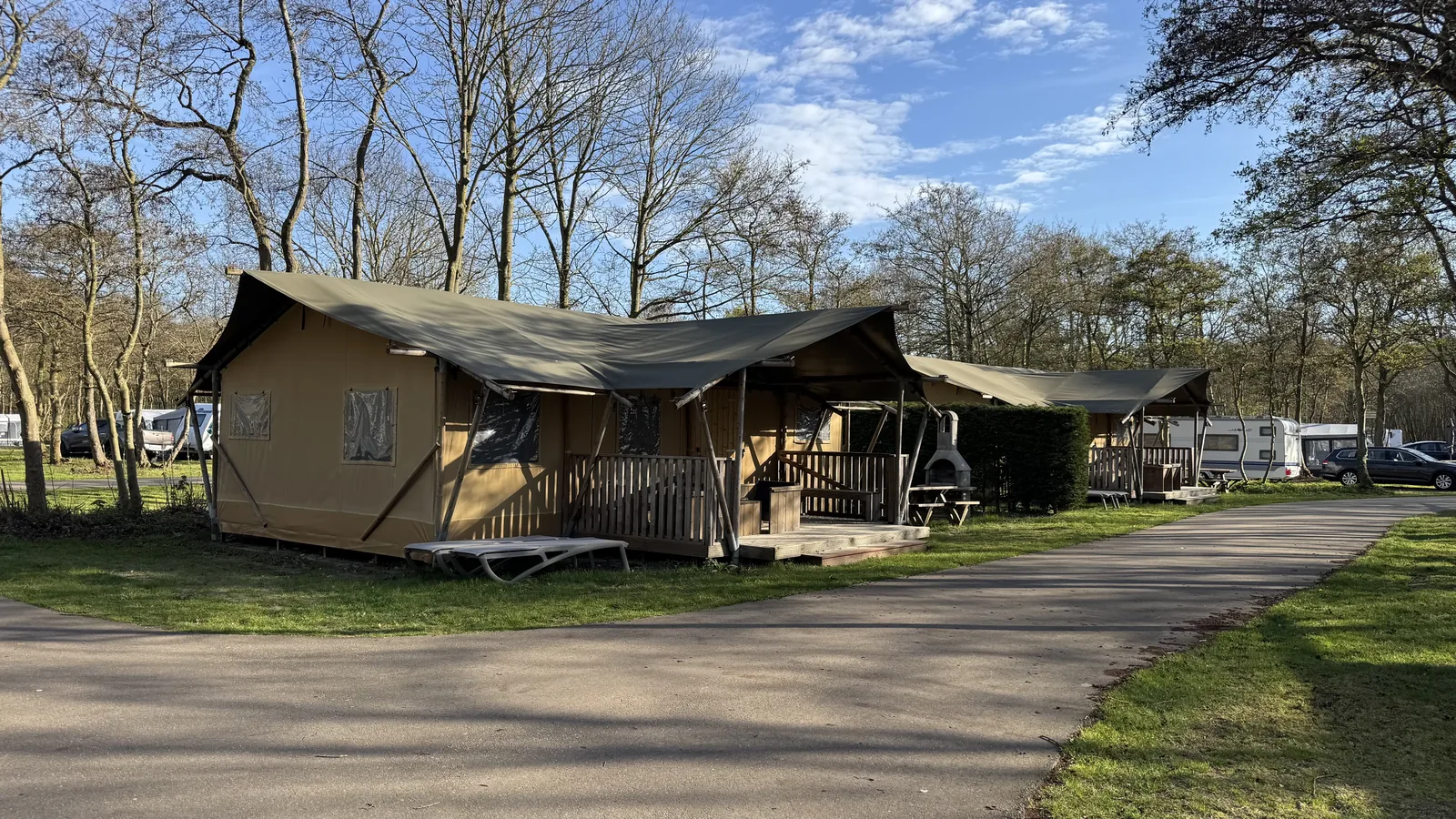 Safarizelt mit Holzterrasse und Sonnenliegen am Rand des Campingplatzes