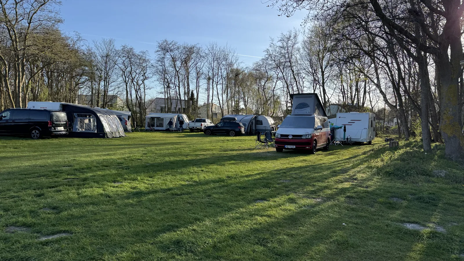 Sonnige Stellplatzwiese mit Campingbus mit Aufstelldach, Wohnwagen und Wohnmobilen