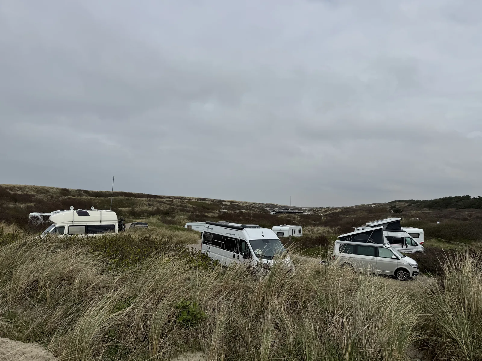 Reihe von Campingbussen und Wohnmobilen im Dünengelände von Camping Kogerstrand