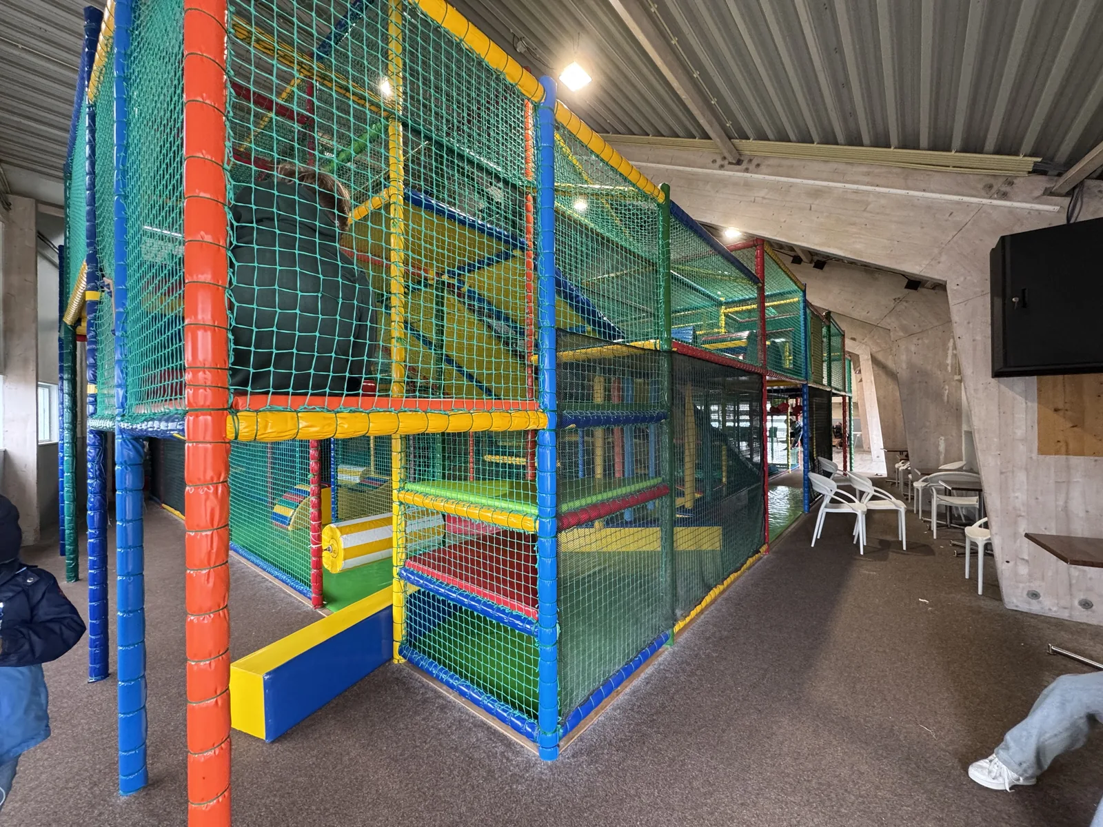 Buntes Indoor-Klettergerüst mit Netzen und Rutsche in der Spielhalle von Camping Kogerstrand