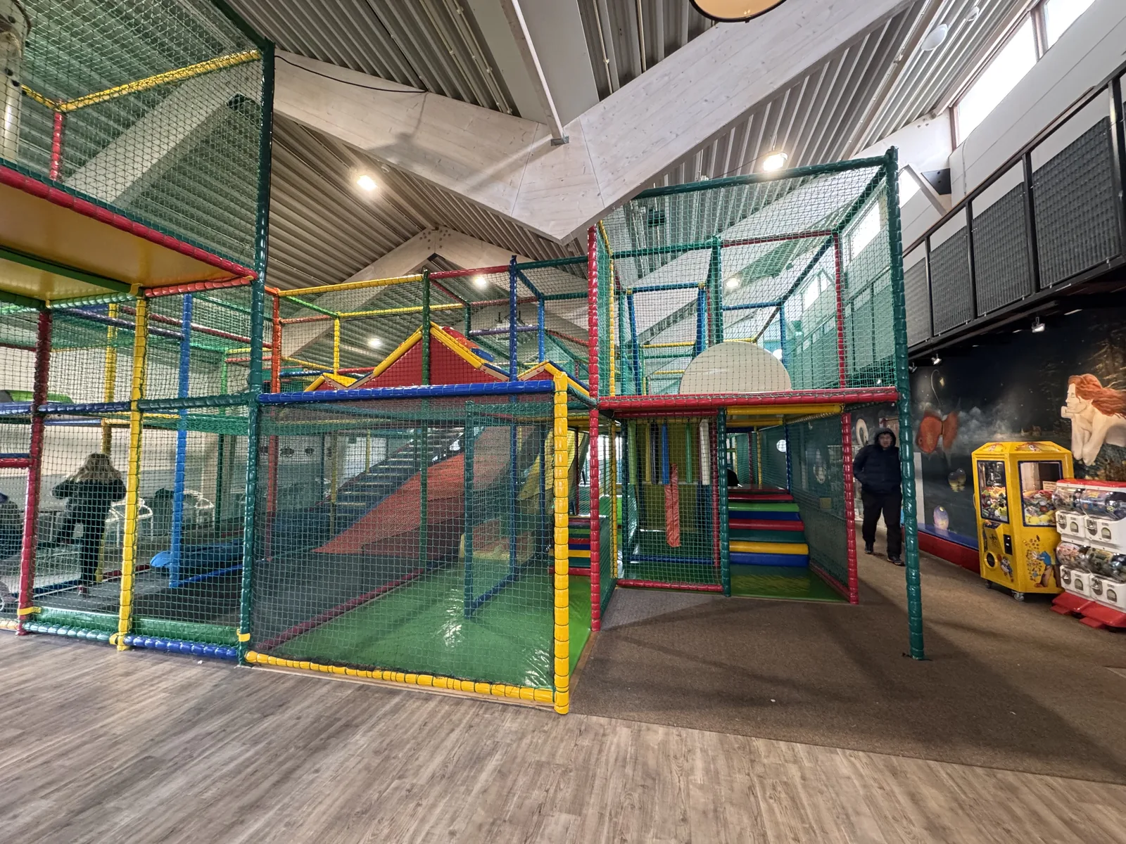 Indoor-Spielgerüst mit roter Rutsche, daneben Spielautomaten in der Halle auf Camping Kogerstrand