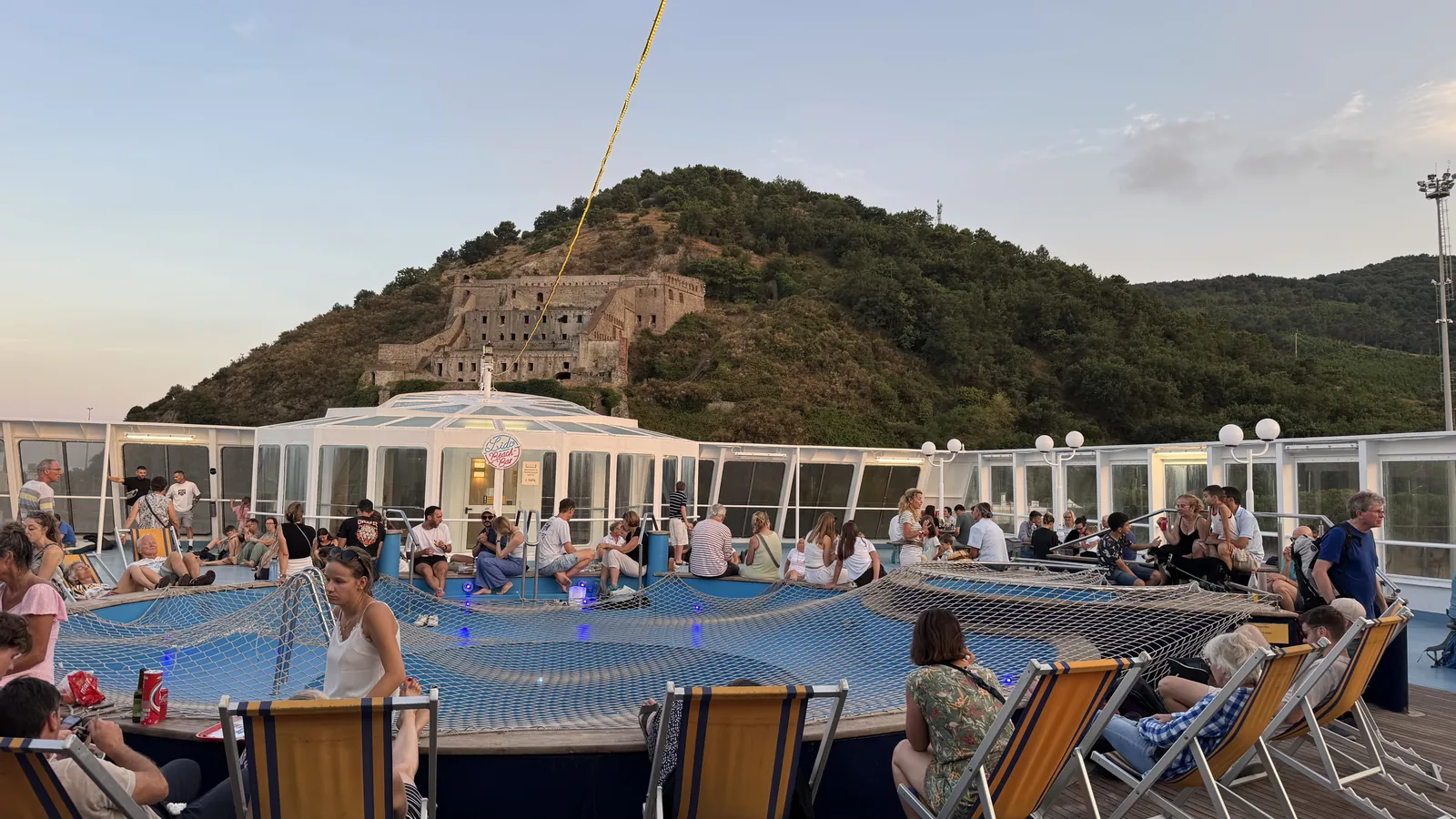 Pool auf dem Sonnendeck der Fähre, im Hintergrund eine Küste mit Zitadelle