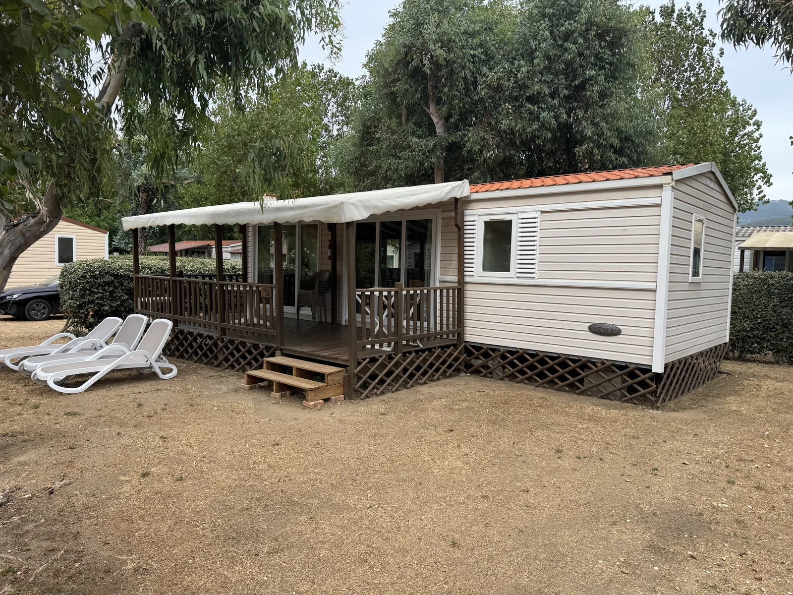 Mobilheim mit überdachter Terrasse und Liegen am Camping A Marina