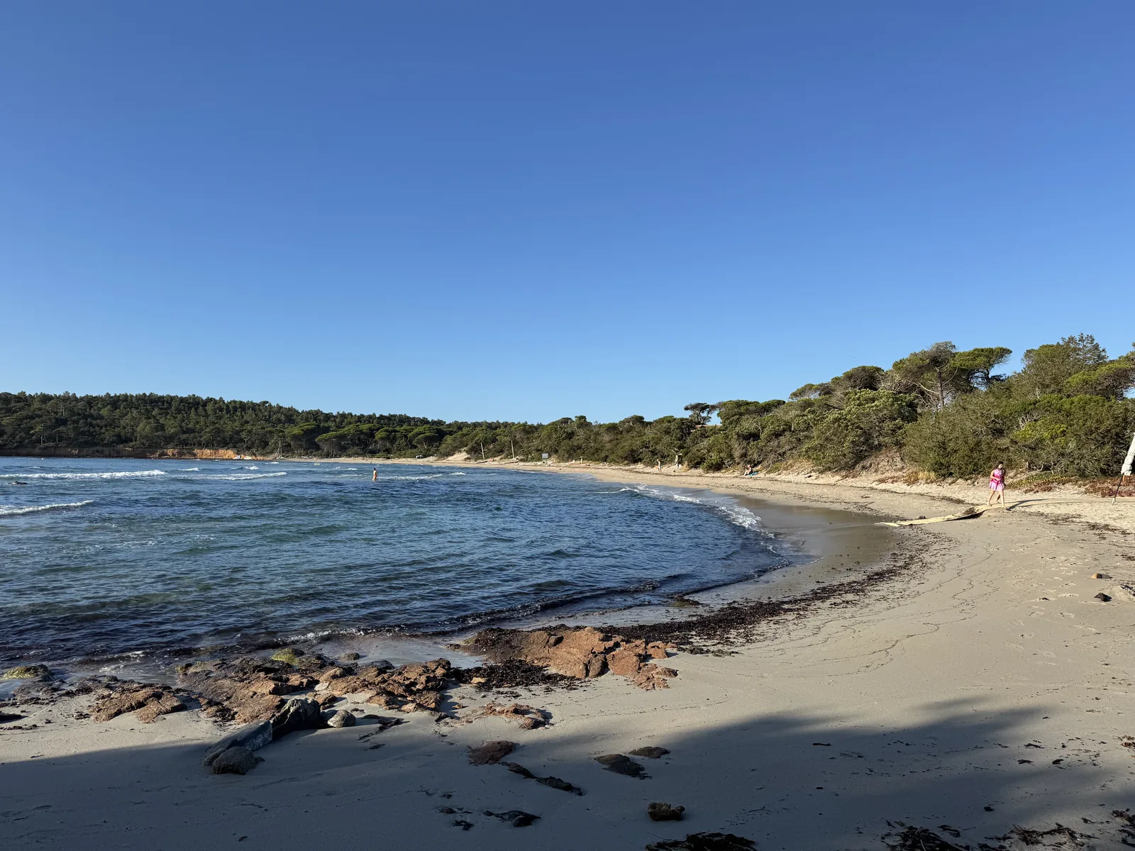 Türkisblaue Bucht von Pinarello mit flachem Sandstrand und bewaldeten Hügeln am Camping California auf Korsika