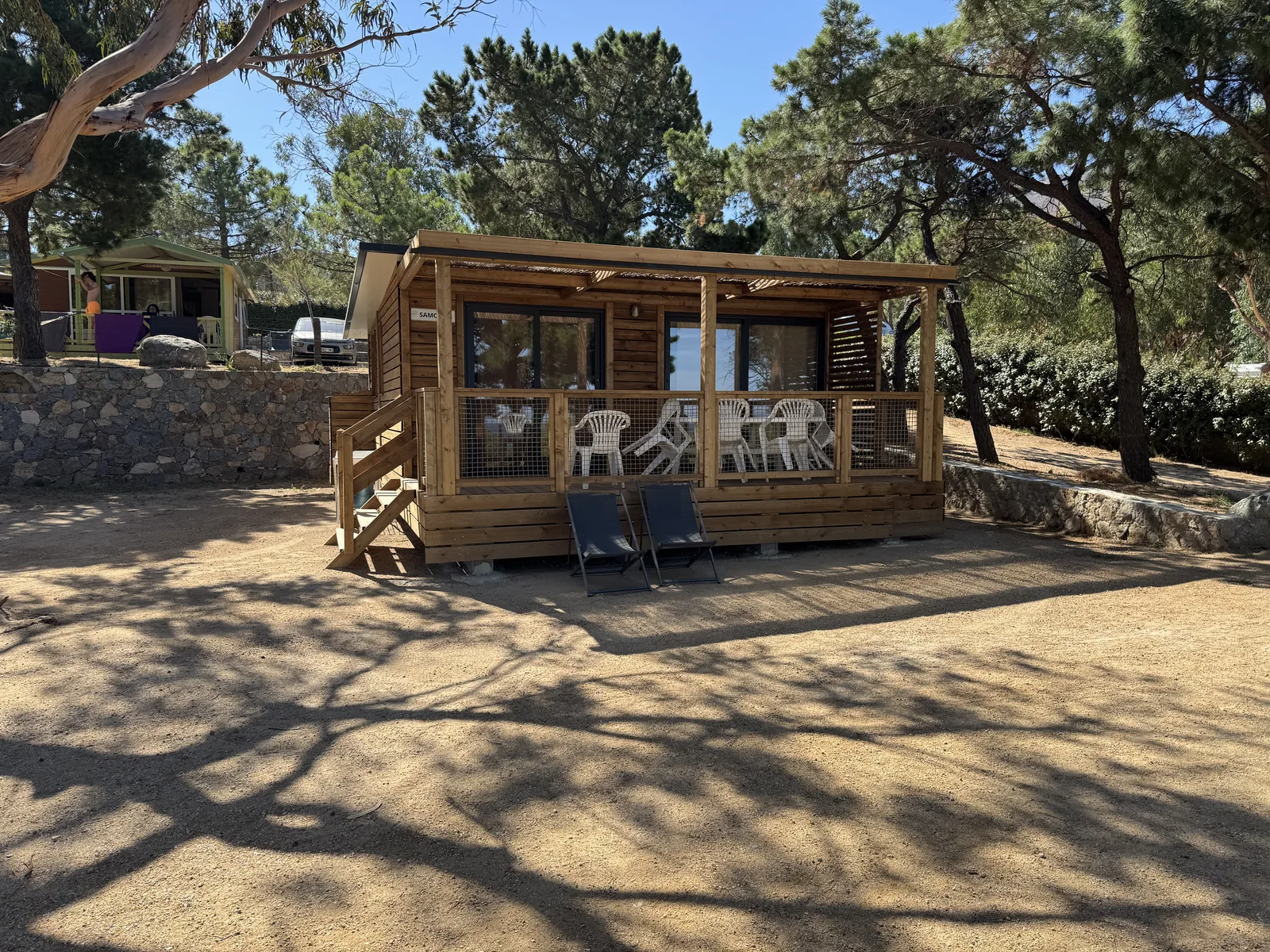 Mietchalet mit überdachter Terrasse und Stühlen am Camping Le Bodri