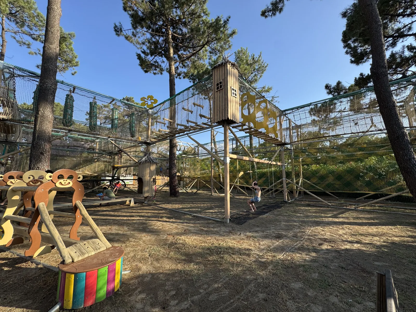 Großer Abenteuerspielplatz mit Kletterparcours und Federtieren unter Pinien am Camping San Damiano