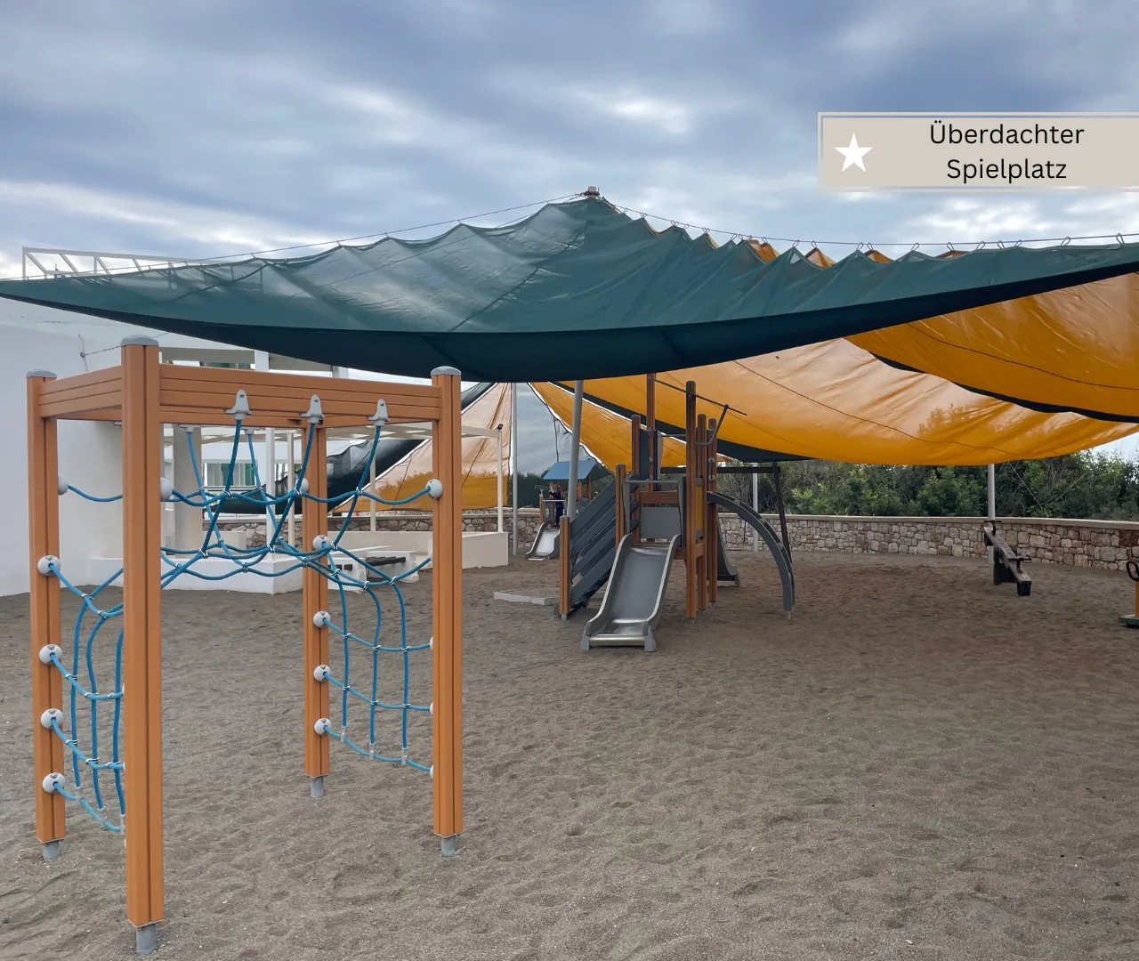 Zweite Ansicht des überdachten Spielplatzes mit Rutsche und viel Sand