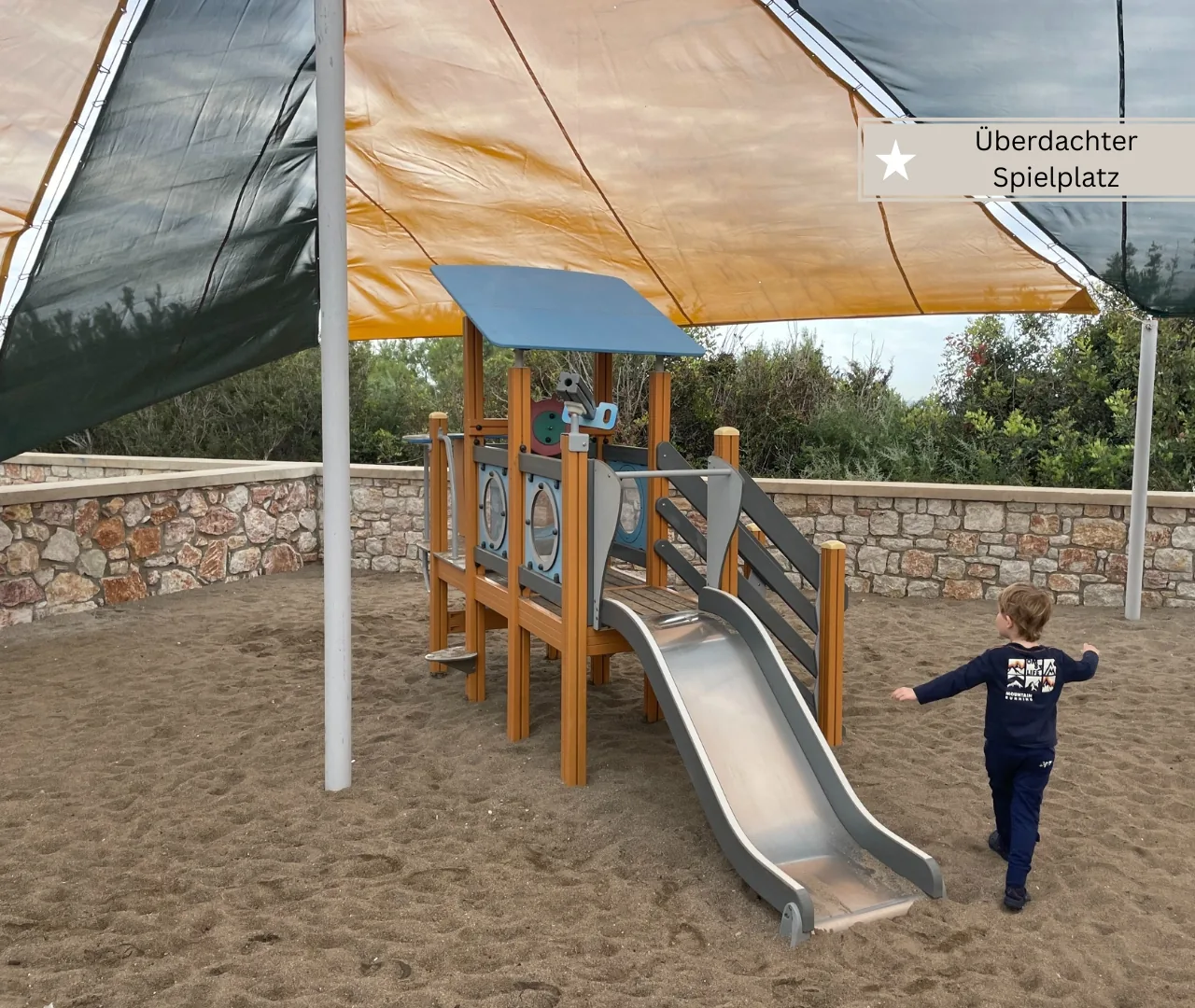 Überdachter Spielplatz mit Klettergerüst auf Sandboden