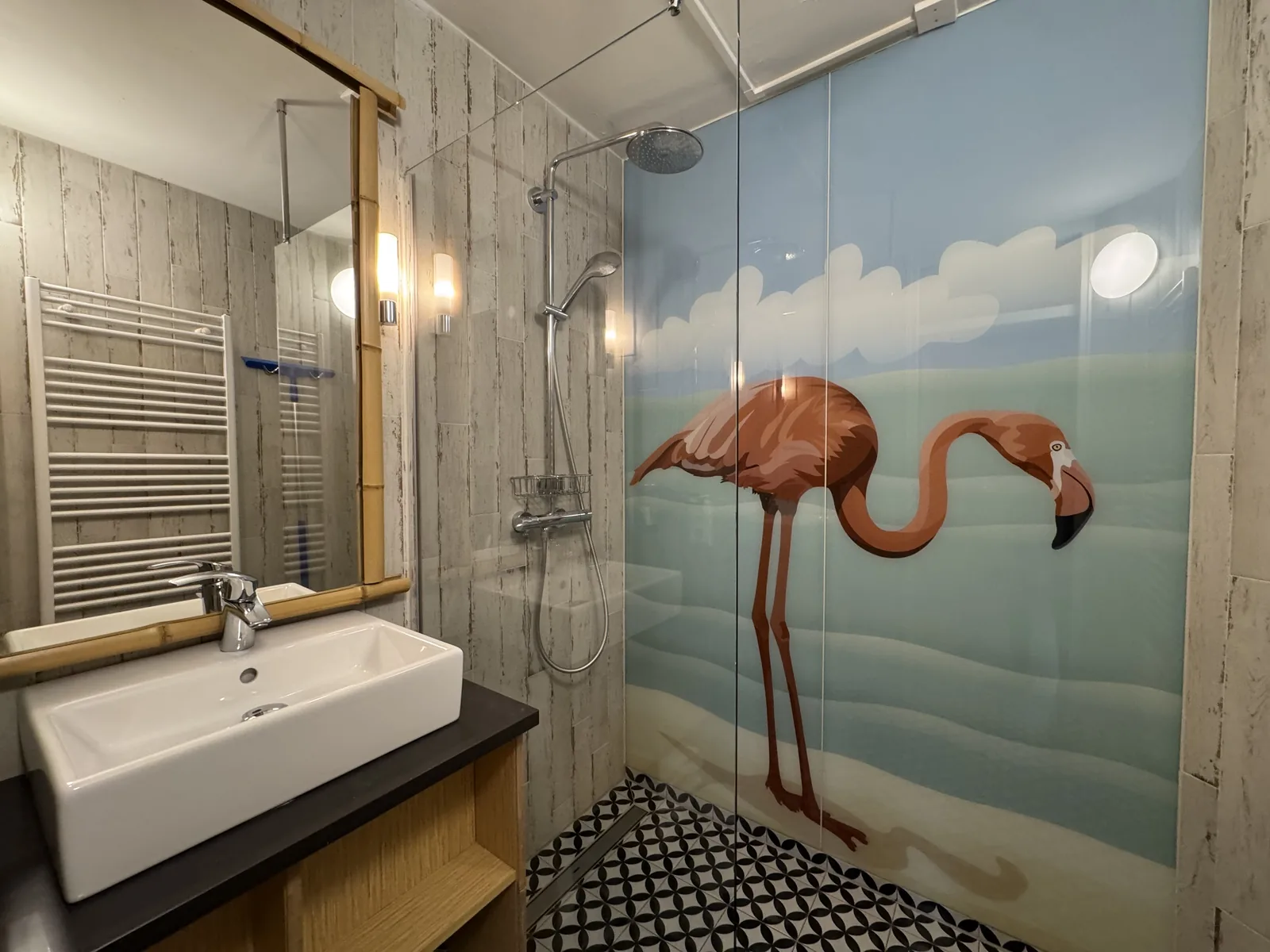Badezimmer der Beach Chilla mit Waschbecken, Handtuchheizkörper und großem Flamingo-Motiv an der Wand