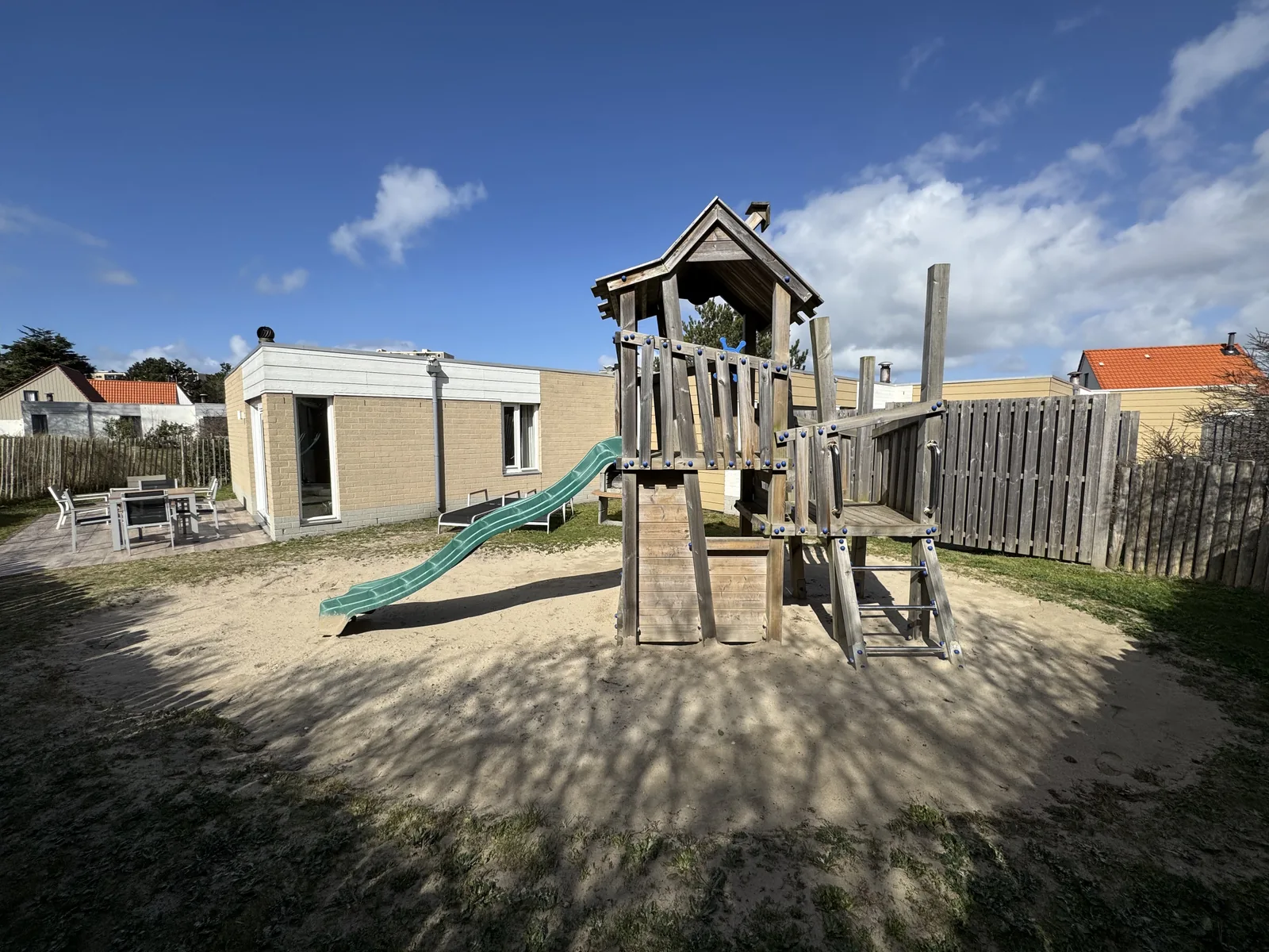 Spielturm mit Rutsche vor der Reihe der Beach-Chilla-Ferienhäuser mit Terrassen