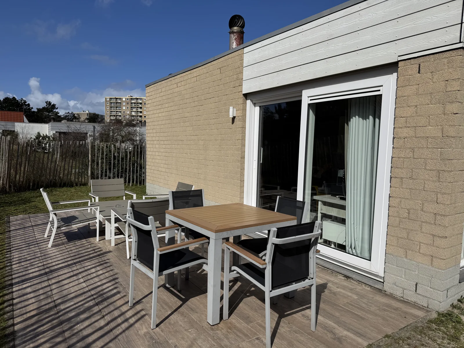 Holzterrasse vor der Terrassentür der Beach Chilla mit Esstisch und vier Gartenstühlen