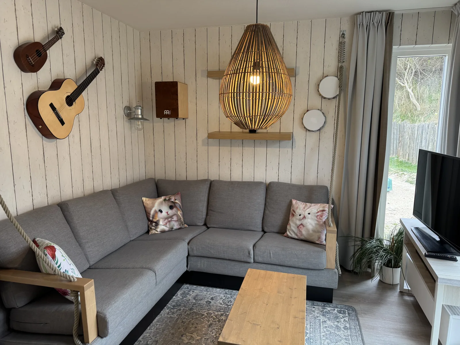 Wohnzimmer der Beach Chilla mit grauem Ecksofa, zwei Gitarren als Wanddeko und Rattanlampe