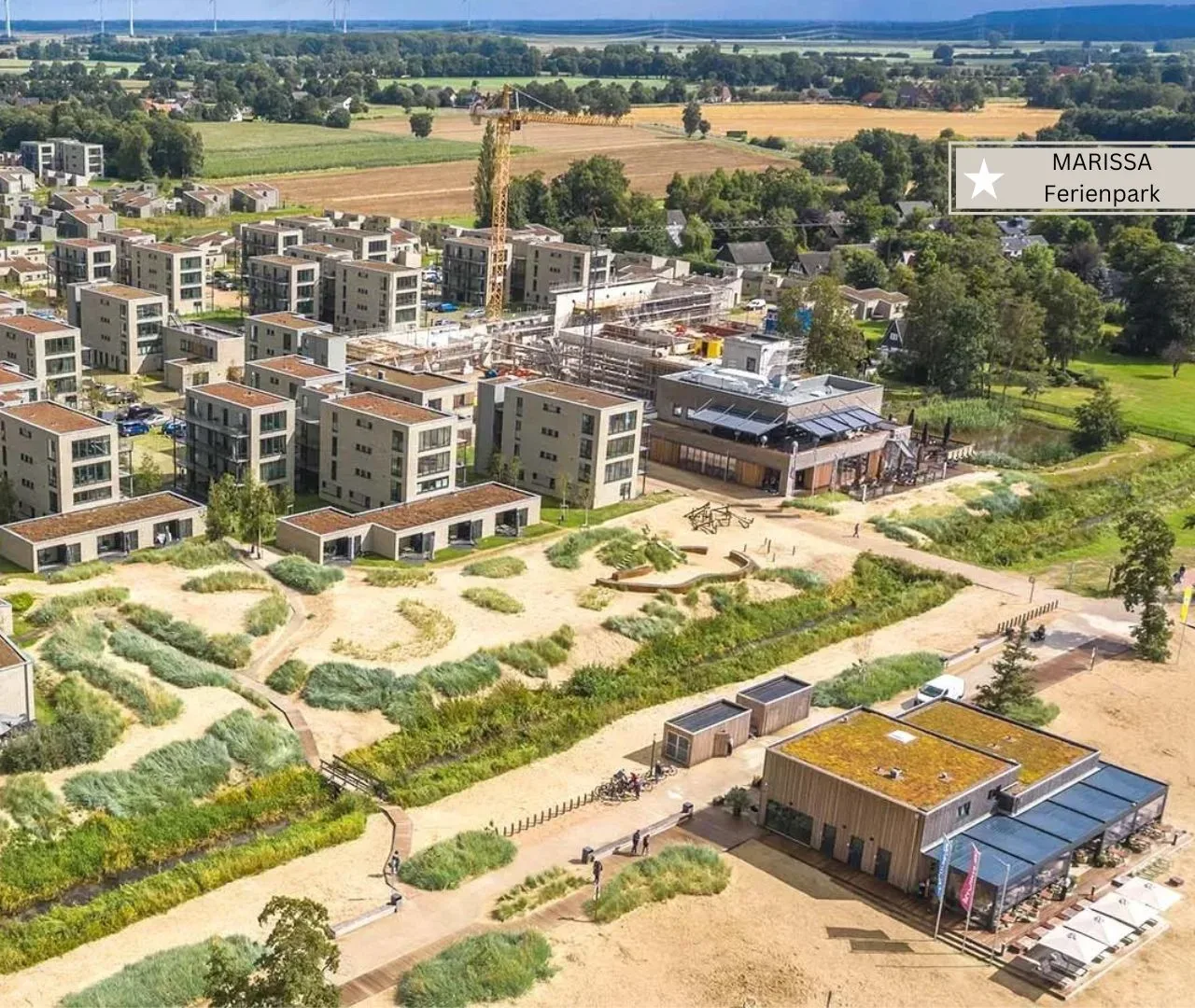 Luftbild des Marissa Ferienparks mit Apartmenthäusern, flachen Ferienhäusern und angelegter Dünenlandschaft