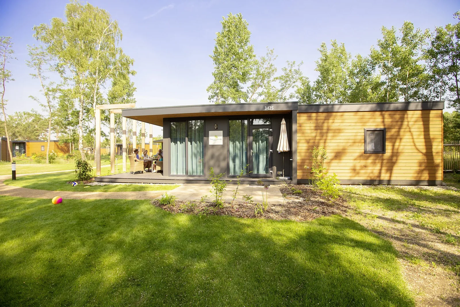 Modernes Ferienhaus aus Holz mit Terrasse und Wiese im Tropical Islands