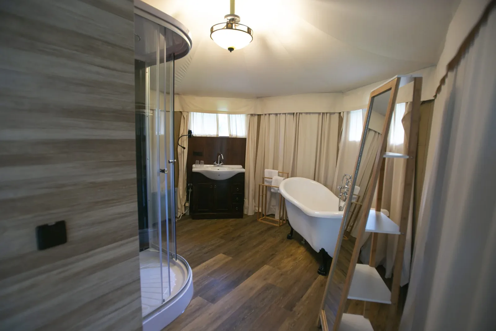 Badezimmer in einem Luxuszelt mit Dusche, Waschtisch und freistehender Badewanne
