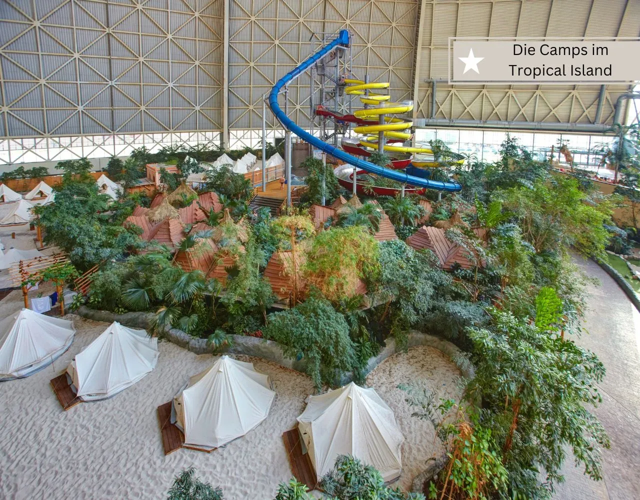Safarizelte auf Sand in der Halle des Tropical Islands, dahinter ein Rutschenturm