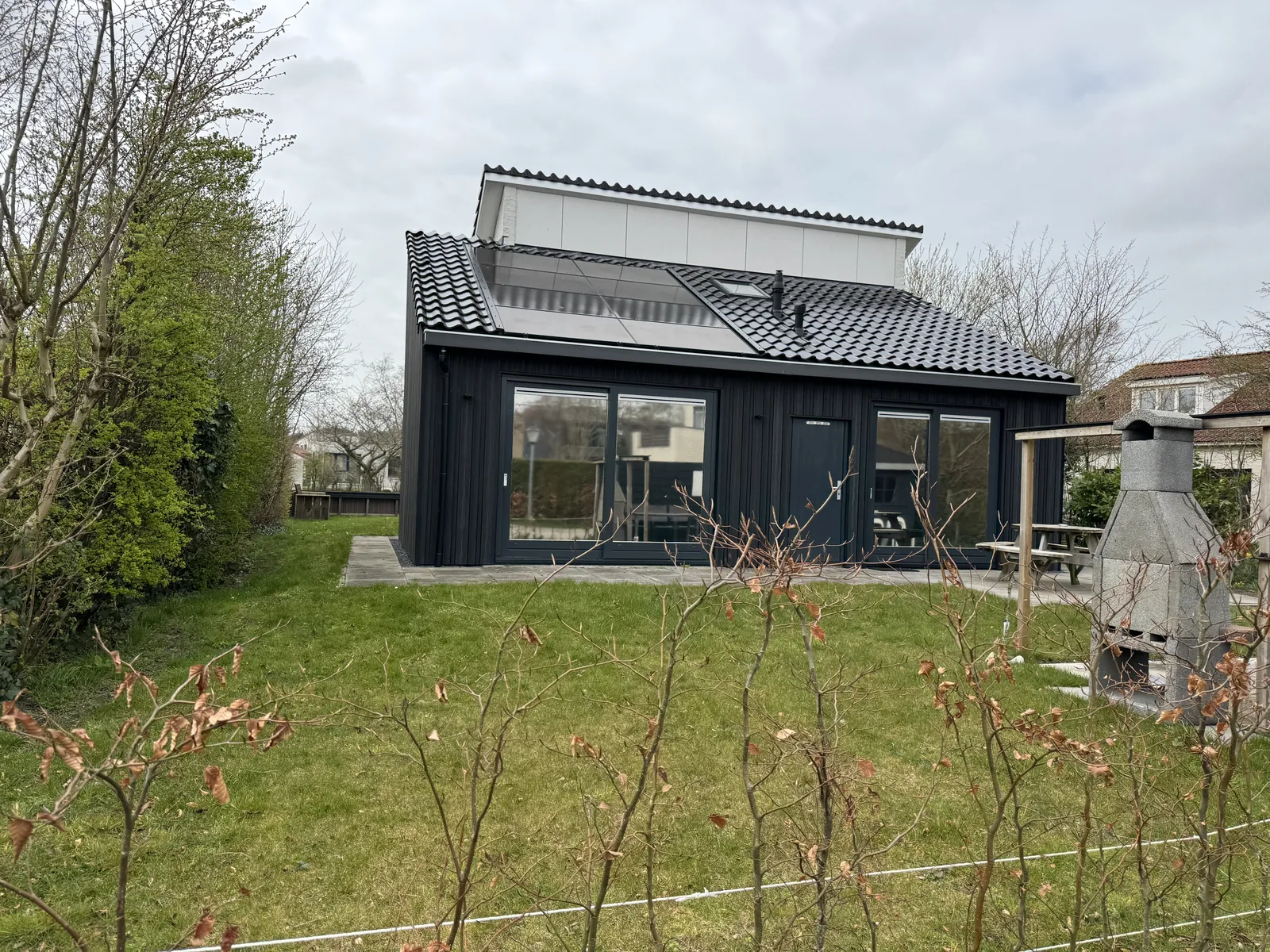 Modernes Ferienhaus mit dunkler Fassade und Flachdach im Ferienpark De Krim, davor eine frisch angelegte Rasenfläche