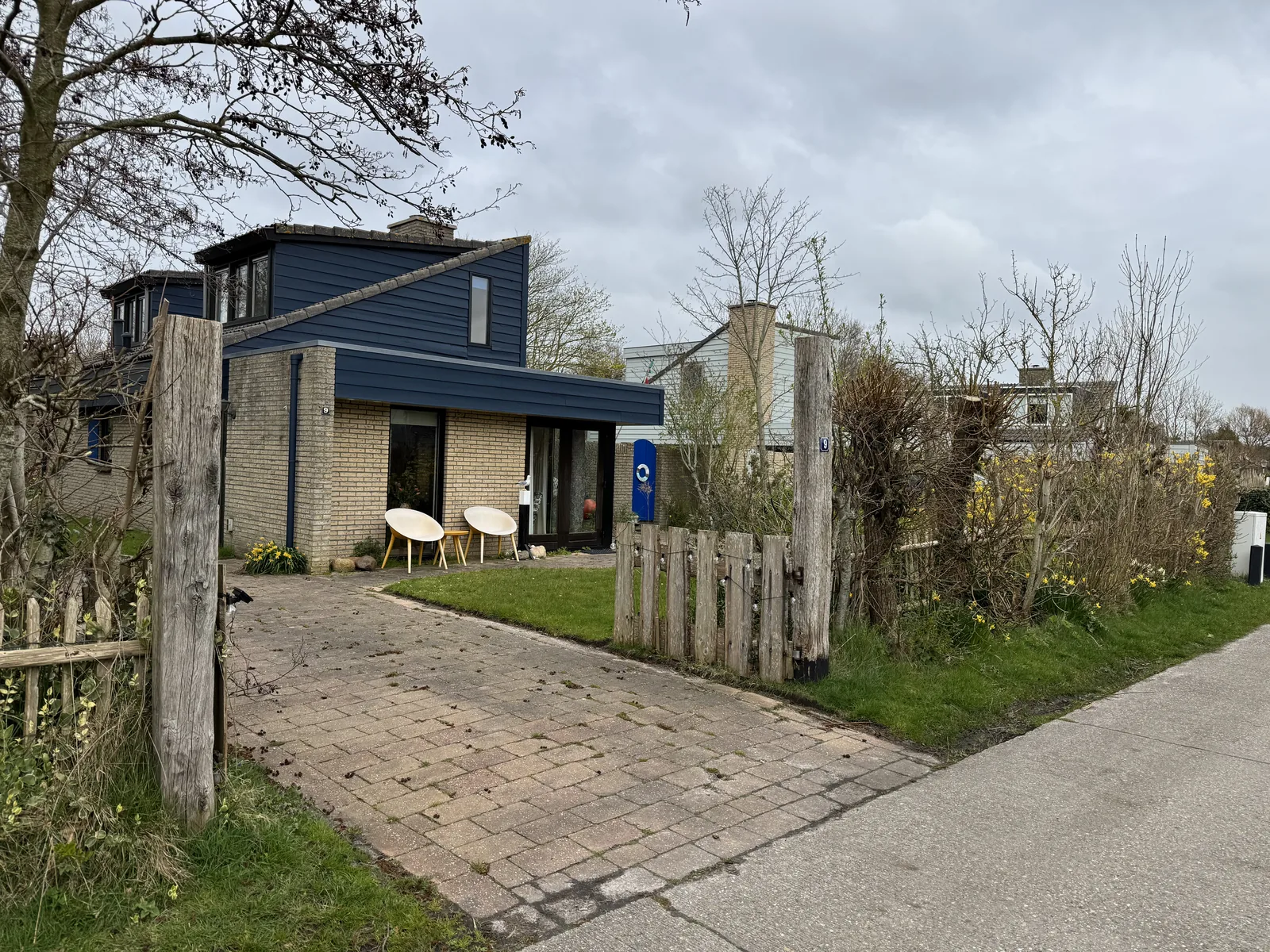 Ferienhaus mit Holzzaun, gepflastertem Zugang und Terrasse im Ferienpark De Krim, dahinter weitere Häuser