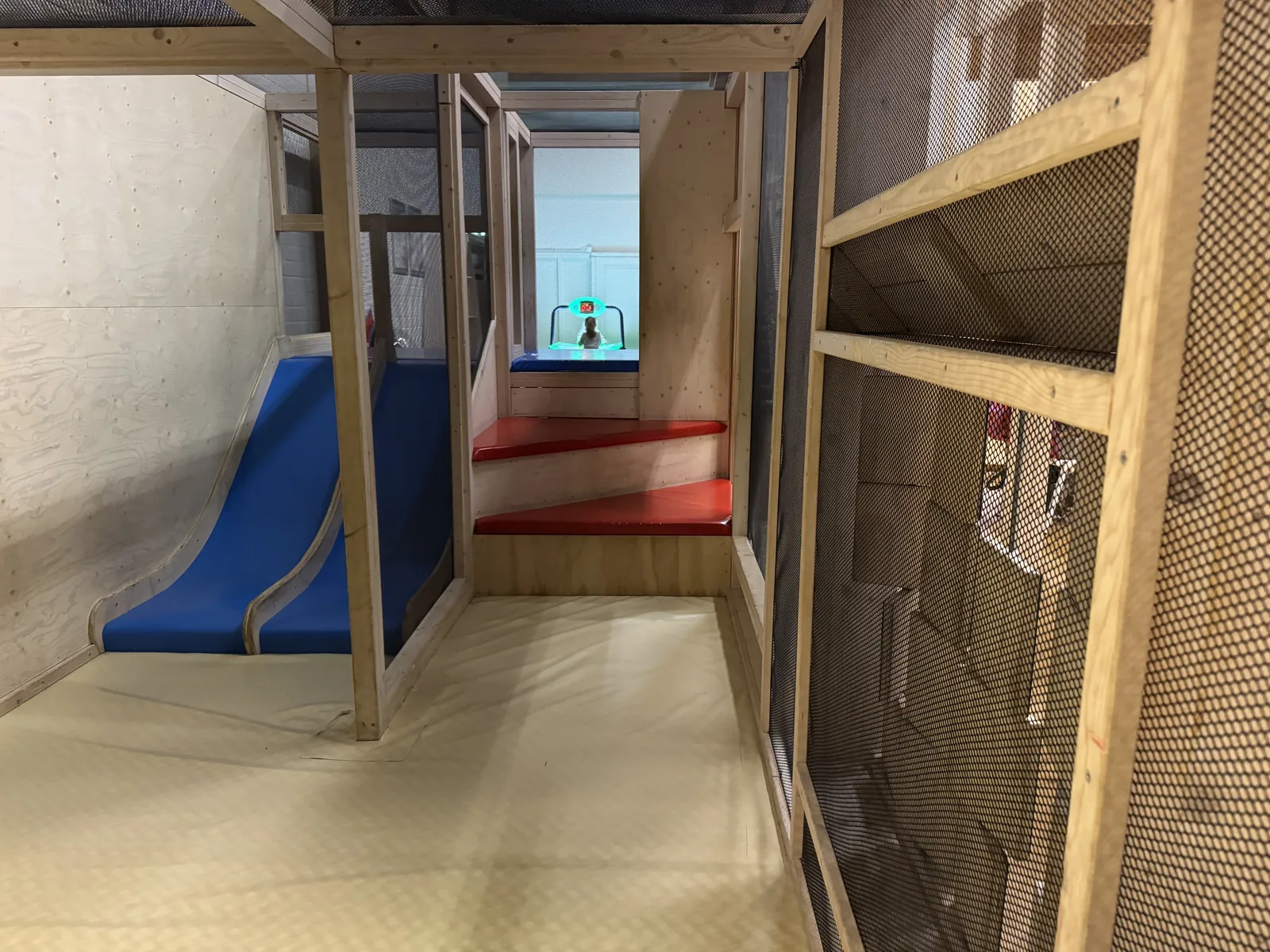 Hölzernes Spielhaus mit blauer Rutsche und Kriechgang im Indoor-Spielbereich des Ferienparks De Krim