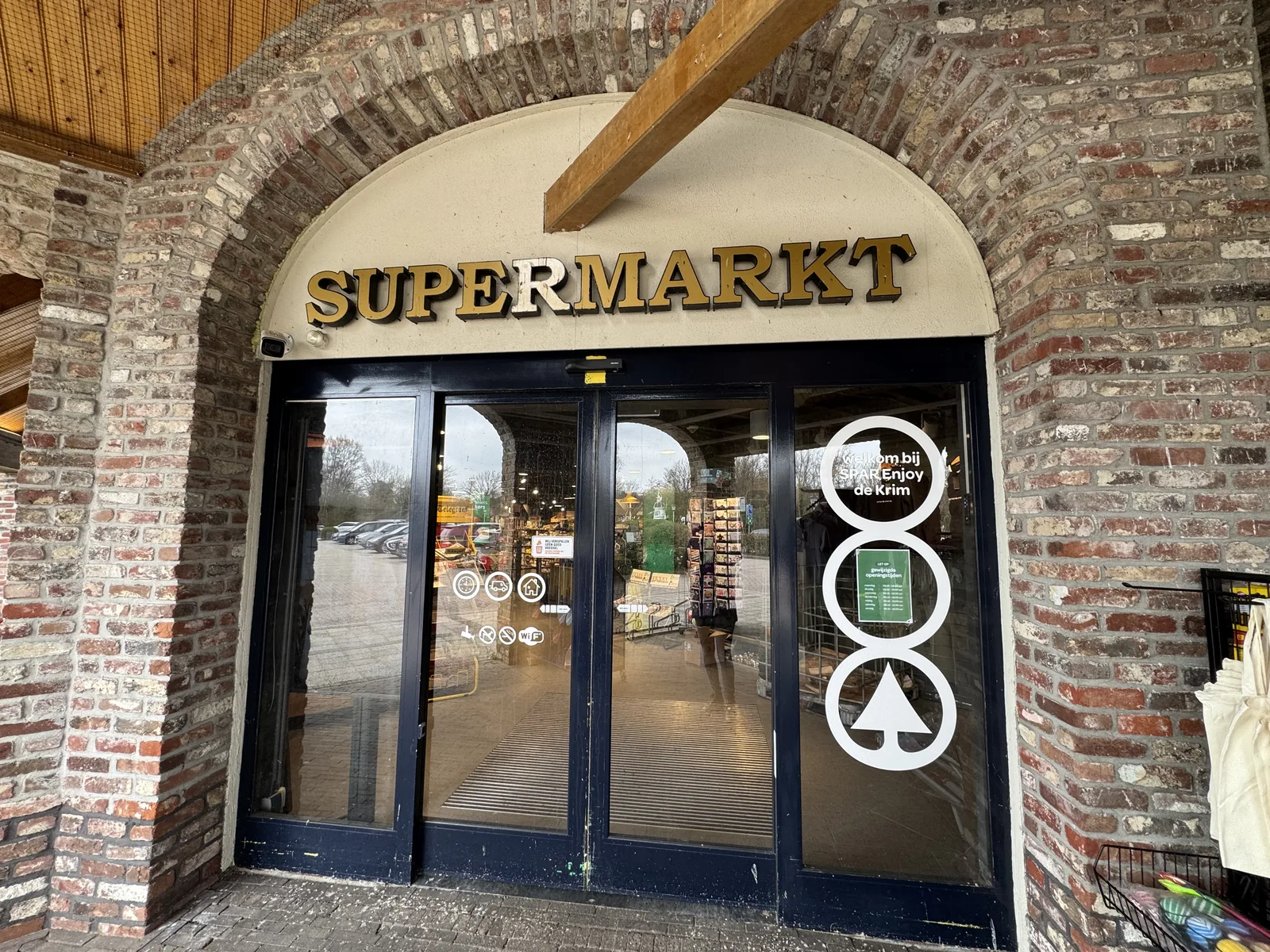 Eingang zum Parksupermarkt unter einem Backsteinbogen mit goldener Aufschrift SUPERMARKT