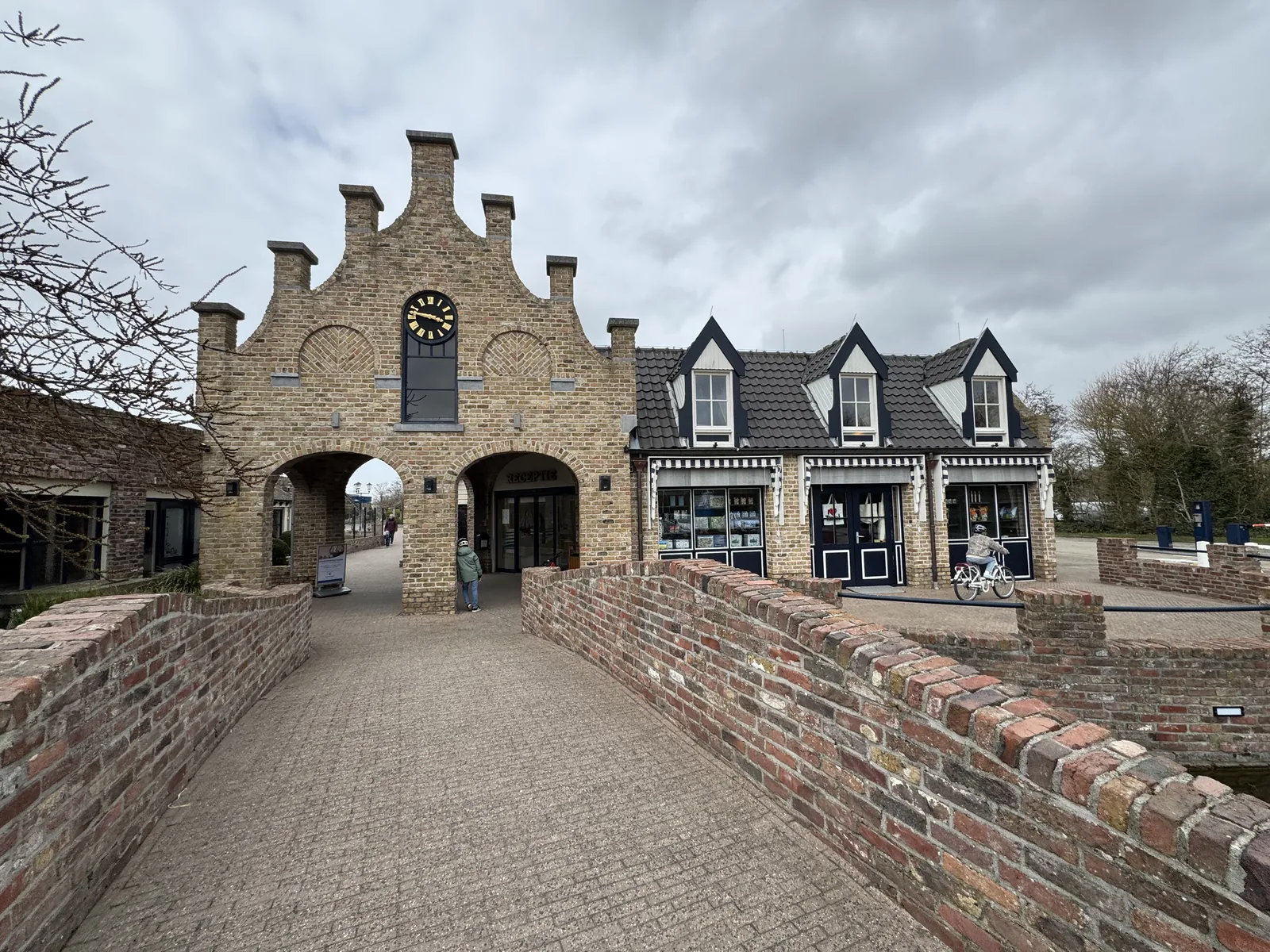 Backstein-Torgebäude mit Uhr am Ende einer kleinen gemauerten Brücke im Zentrum des Ferienparks De Krim auf Texel