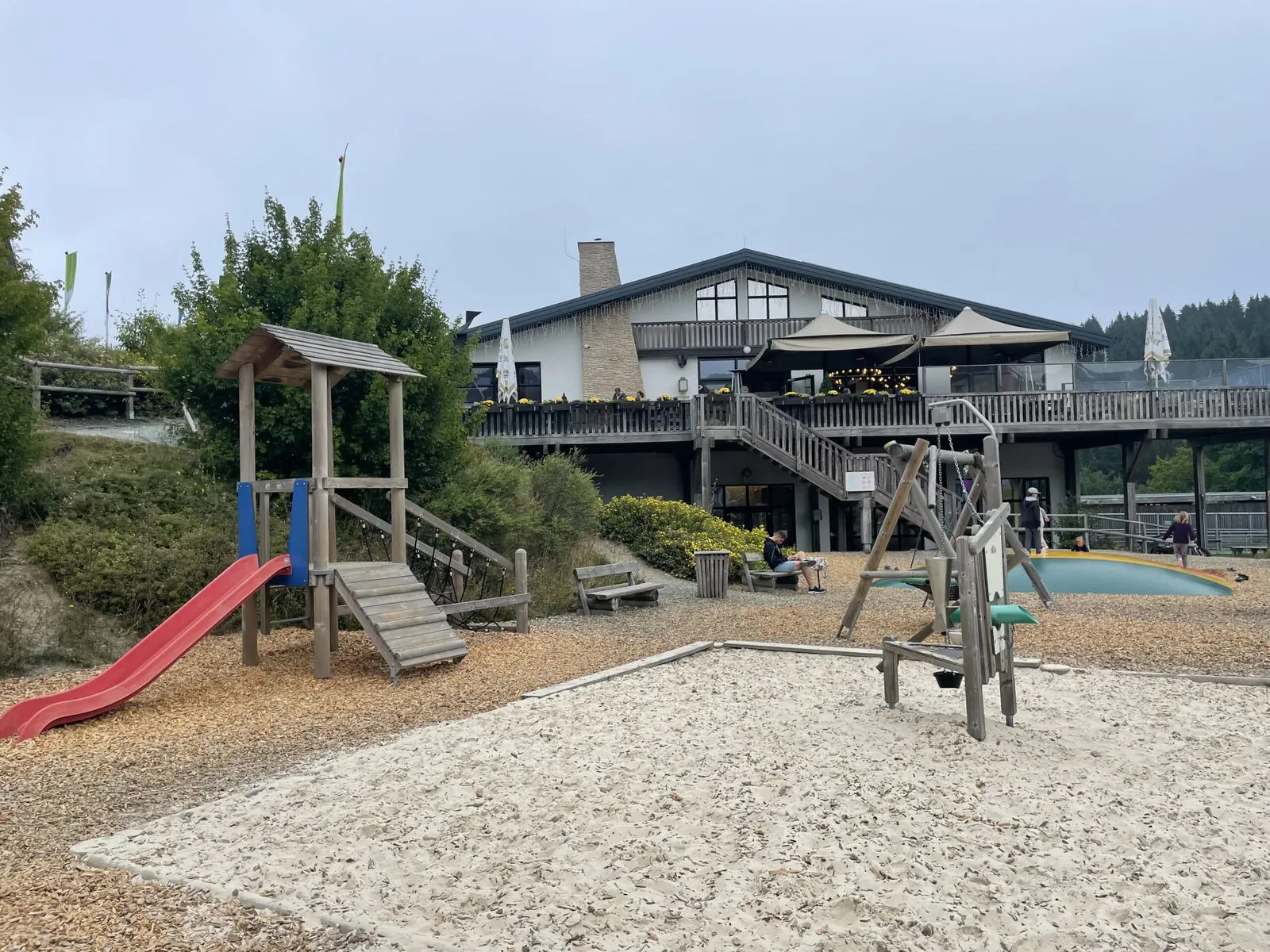Spielplatz mit Rutsche, Sandfläche und Hüpfkissen vor dem Restaurant des Landal Winterberg