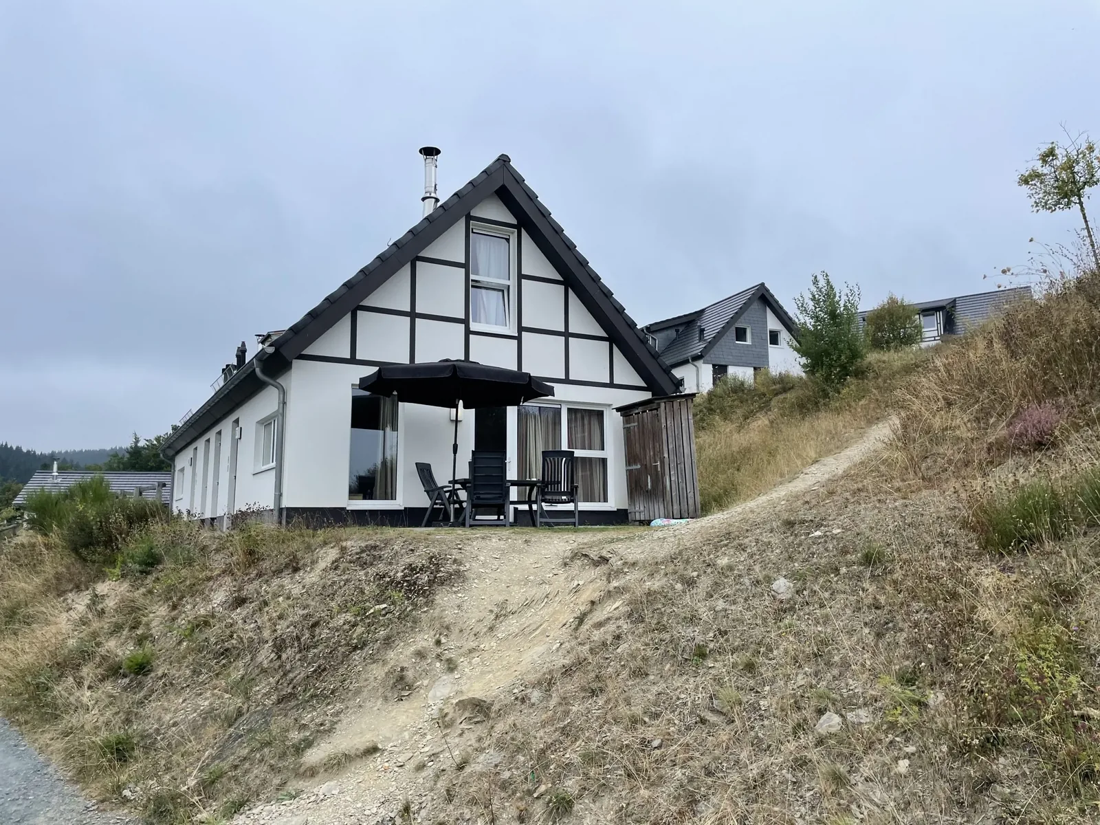 Fachwerk-Ferienhaus im Landal Winterberg am Hang, davor ein steiler Sandweg