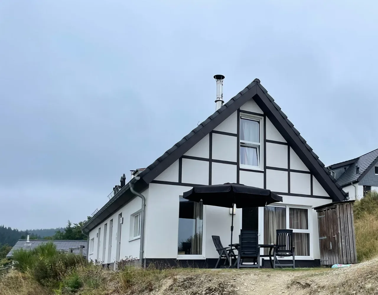 Weißes Fachwerk-Ferienhaus im Landal Winterberg mit Terrasse und Sonnenschirm