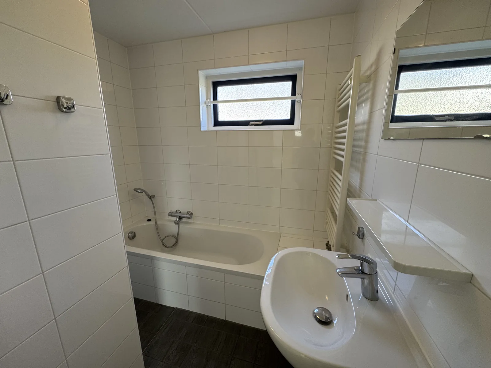 Gefliestes Badezimmer mit Badewanne, Waschbecken und Handtuchheizkörper