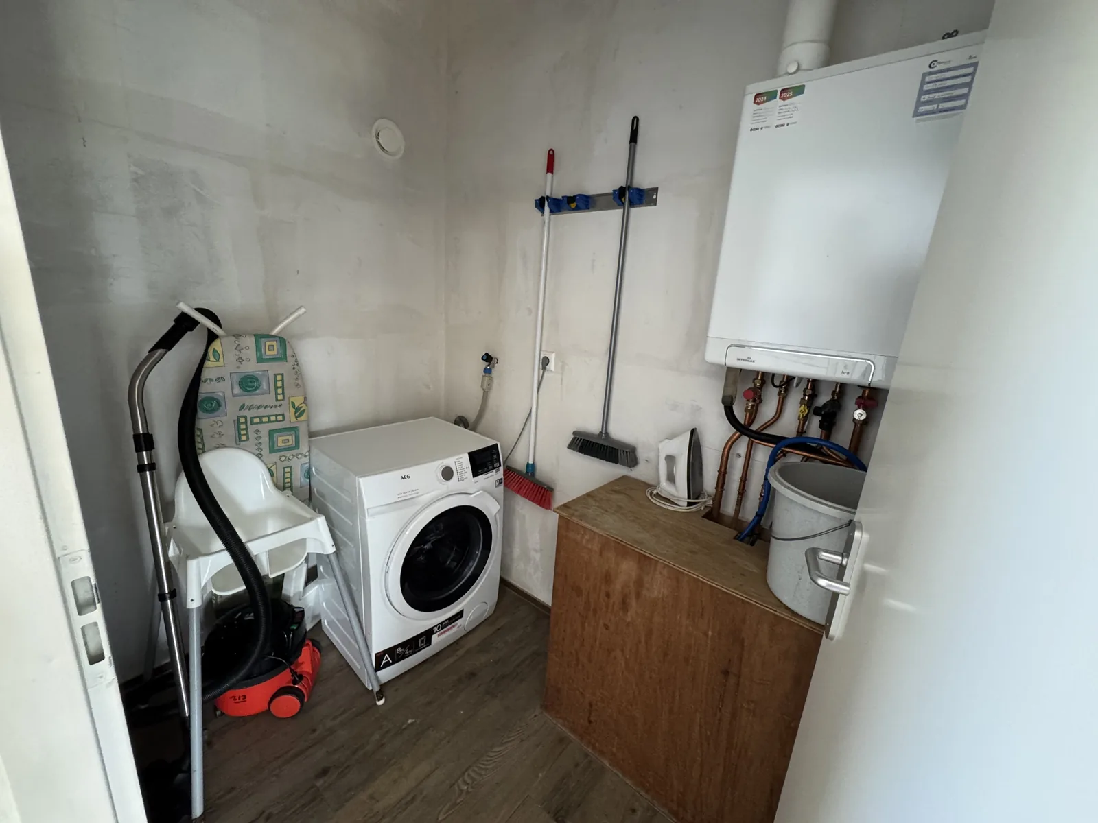 Kleiner Hauswirtschaftsraum mit Waschmaschine, Staubsauger und Wischmopp