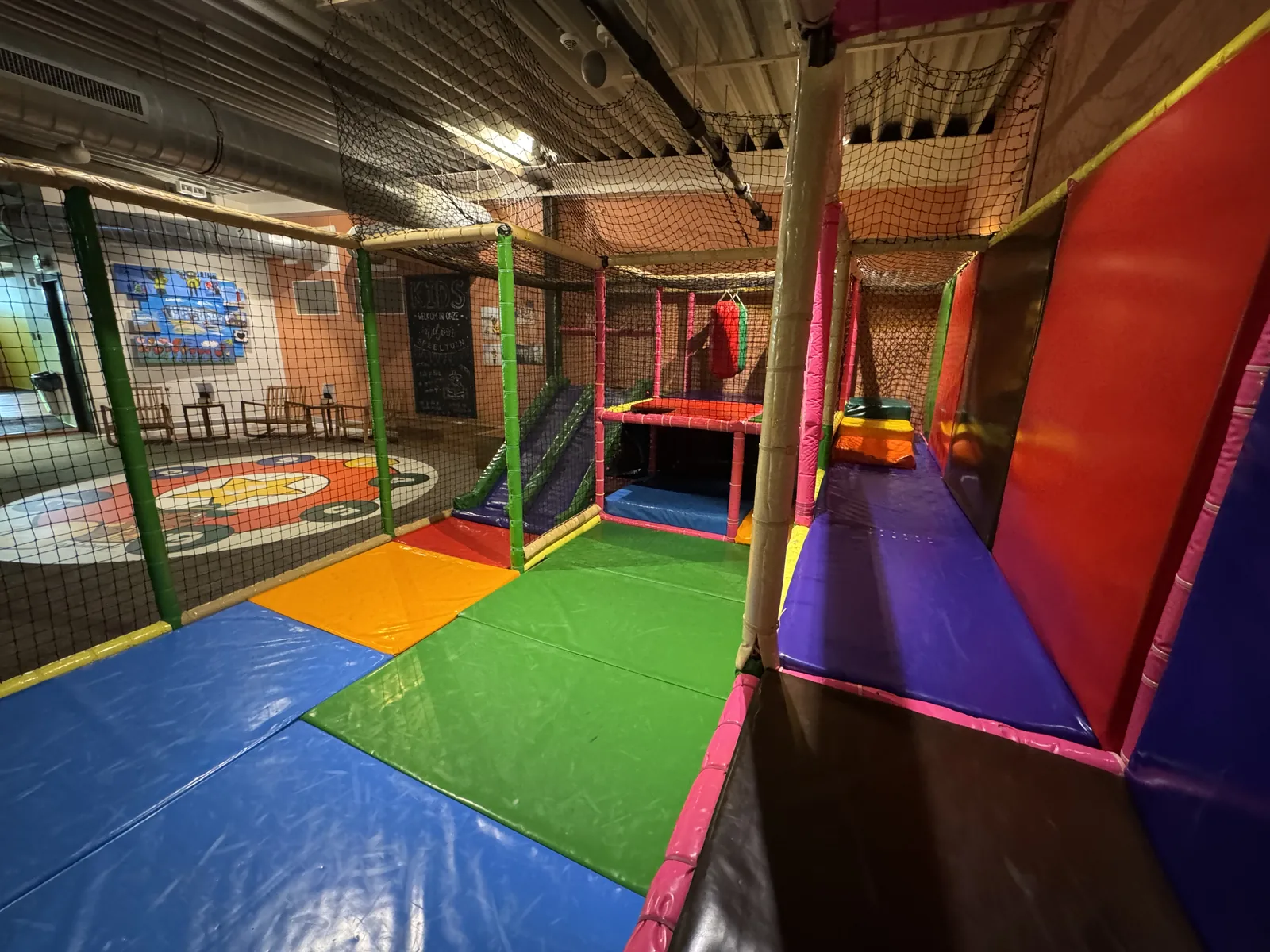 Bunter Indoor-Spielbereich mit weichen Matten, Kletternetz und Tunnel für kleinere Kinder