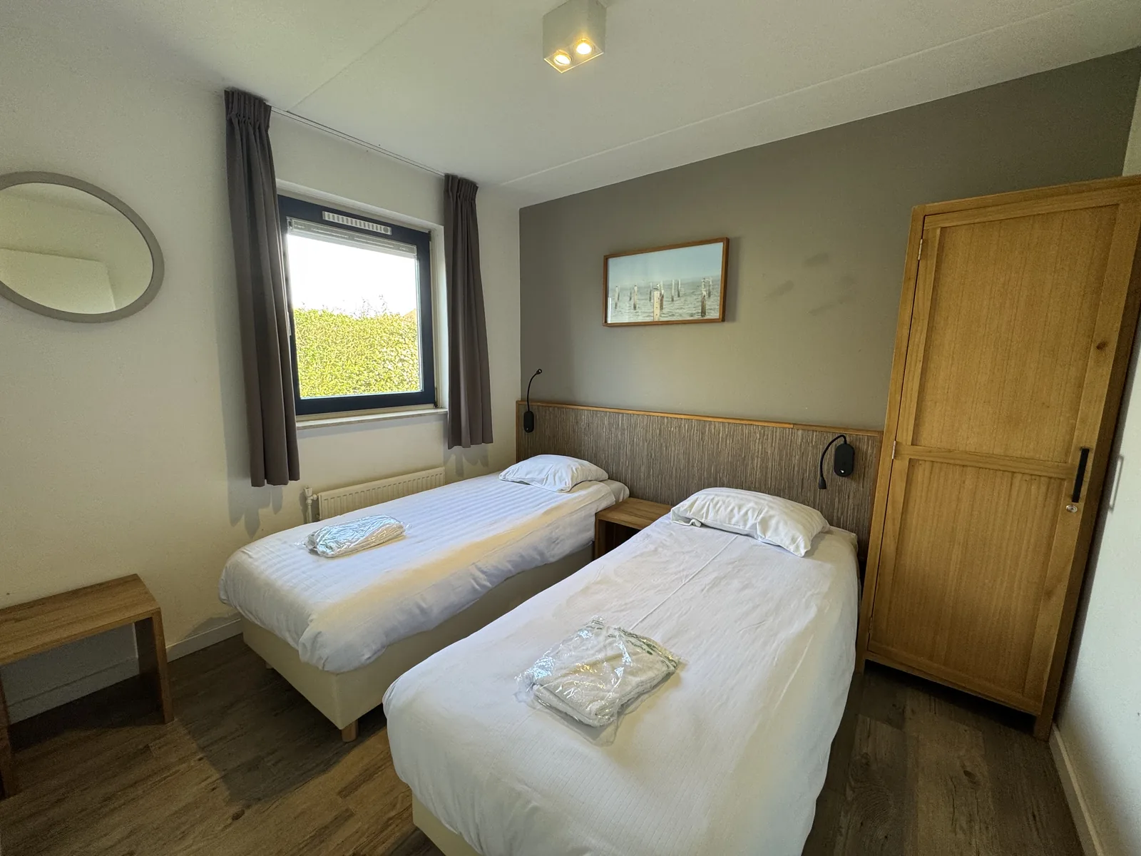 Zweites Schlafzimmer mit zwei Einzelbetten, aufgelegten Handtuchstapeln und heller Holztür unter der Dachschräge