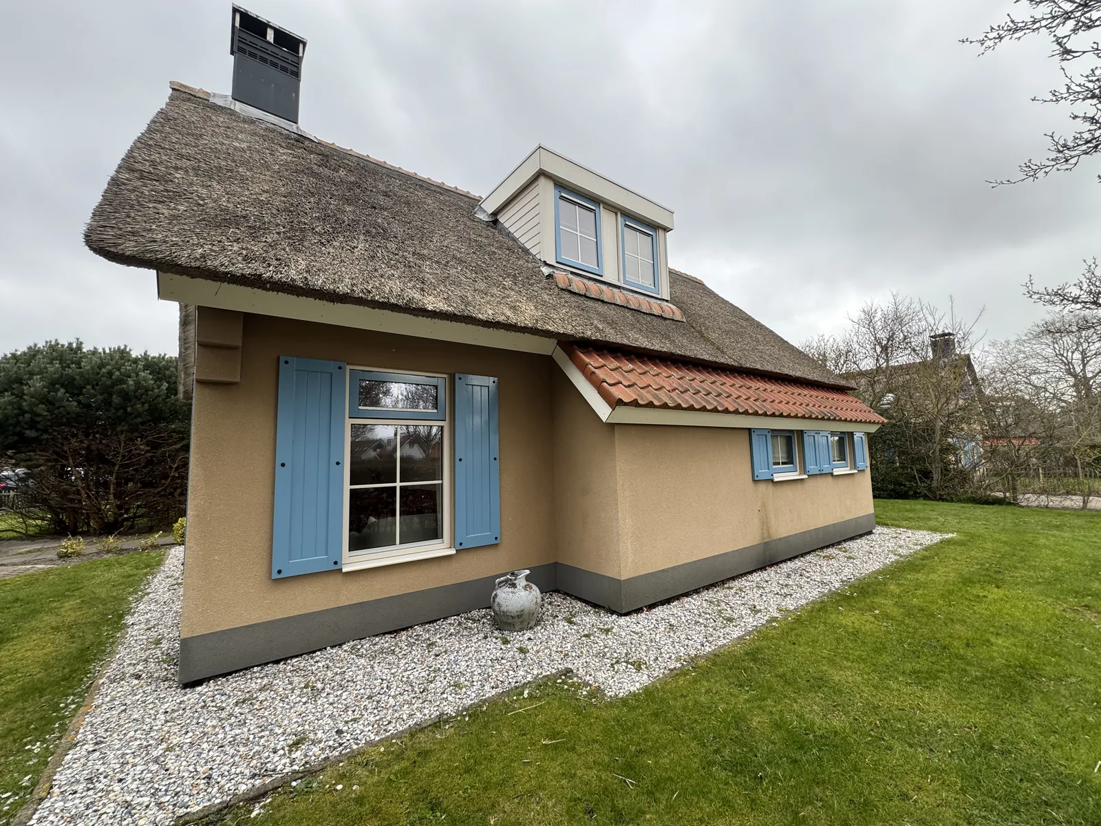 Freistehendes Ferienhaus mit Reetdach und blauen Fensterläden im Landal Kustpark Texel