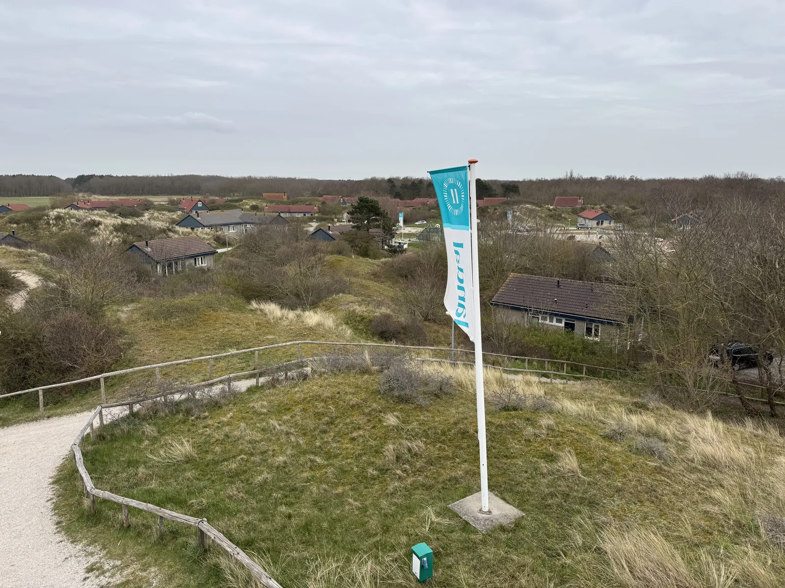 Weites Panorama über die Dünenlandschaft des Landal Sluftervallei mit Sandweg und heller Parkfahne im Vordergrund