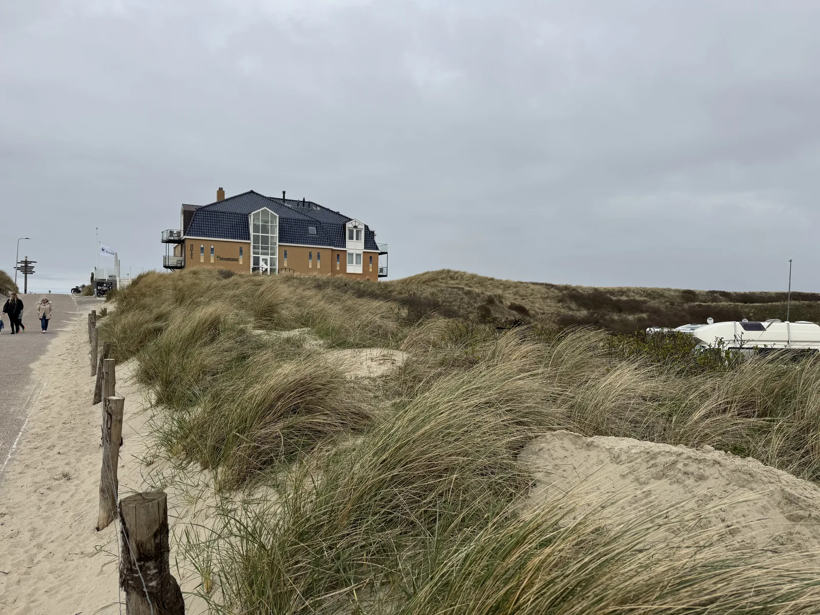 Dünenaufgang zum Strand von De Koog, oben ein großes Appartementhaus