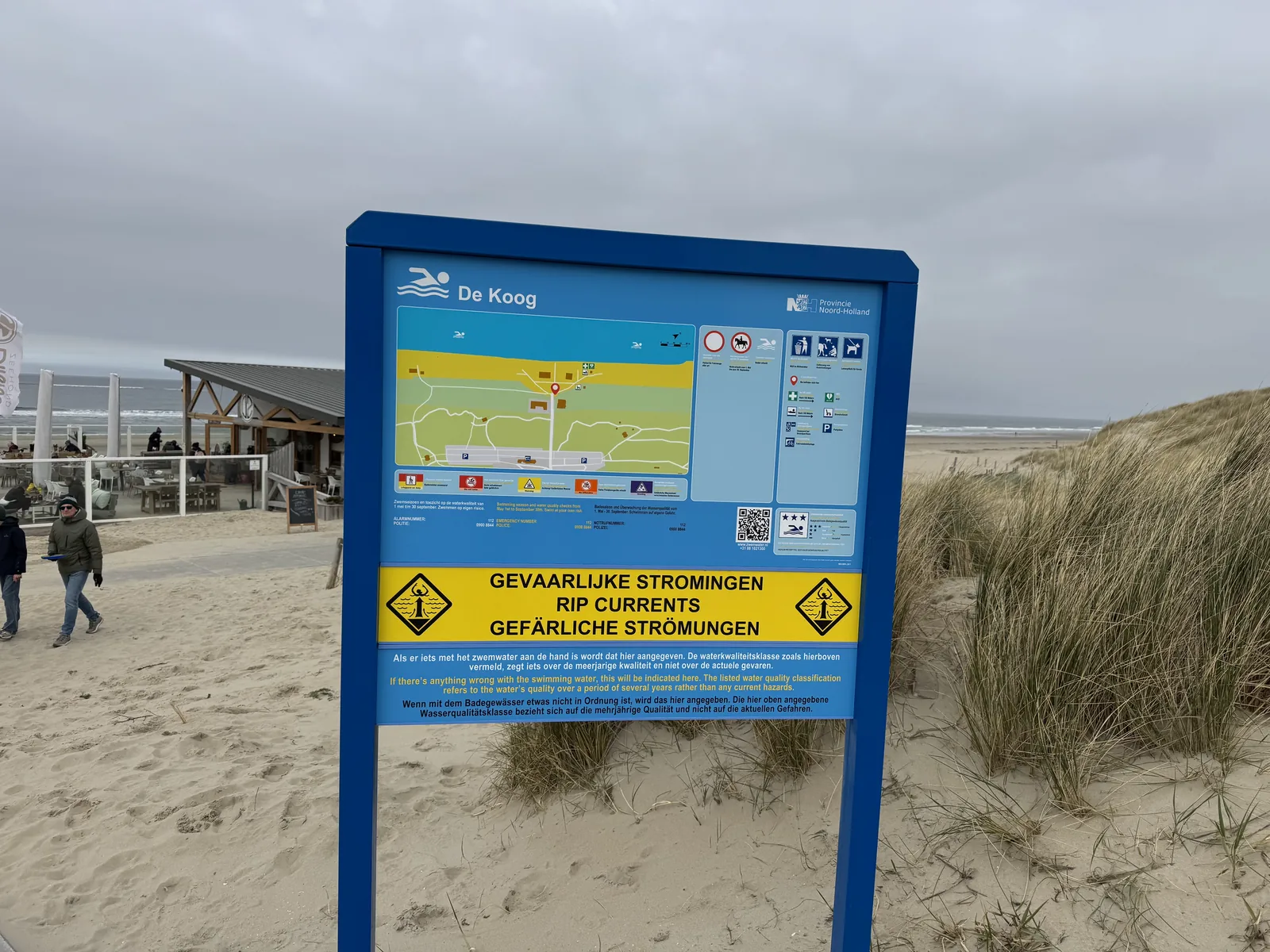 Blaue Informationstafel mit Strandkarte und Warnung vor gefährlichen Strömungen